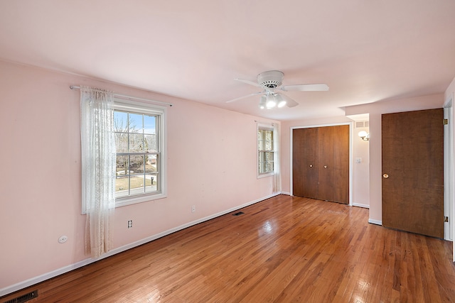 unfurnished bedroom featuring a ceiling fan, wood-type flooring, visible vents, and baseboards