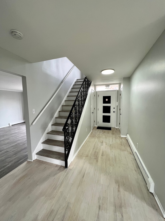 stairs with a baseboard radiator, wood finished floors, and baseboards