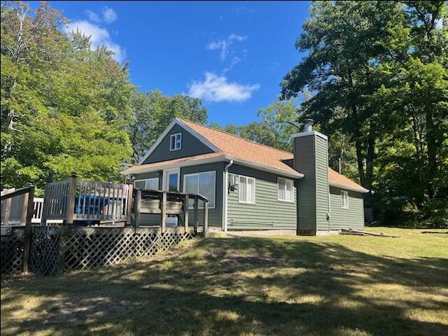 back of house featuring a yard, a chimney, and a wooden deck