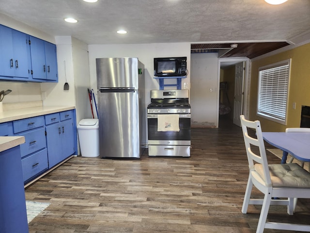 kitchen with a textured ceiling, blue cabinets, light countertops, appliances with stainless steel finishes, and dark wood finished floors