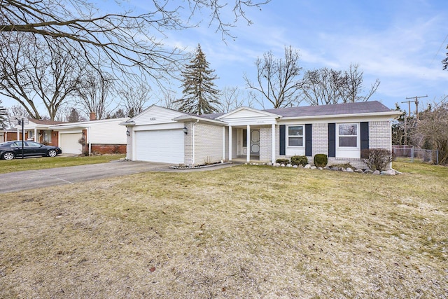 ranch-style home with an attached garage, brick siding, fence, driveway, and a front yard