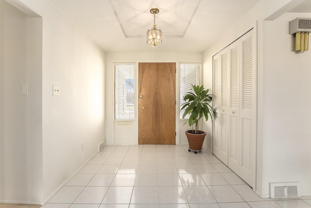 foyer entrance featuring baseboards, light tile patterned flooring, visible vents, and an inviting chandelier