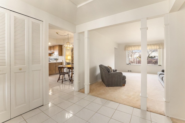 interior space featuring light tile patterned floors, visible vents, light colored carpet, and ornate columns