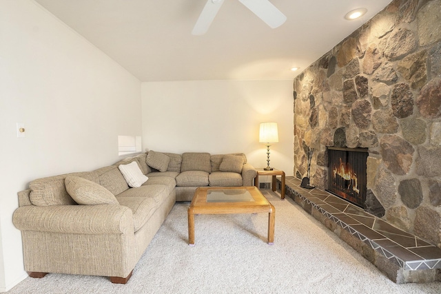 carpeted living room with ceiling fan and a stone fireplace