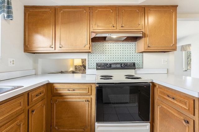 kitchen with under cabinet range hood, light countertops, electric range, and decorative backsplash