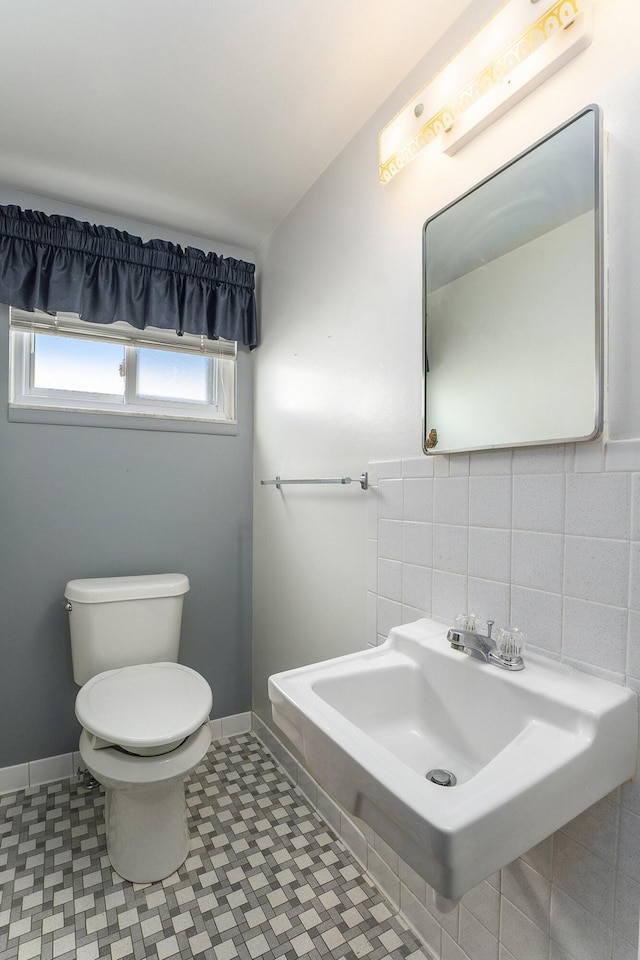 half bathroom with toilet, tasteful backsplash, baseboards, and a sink