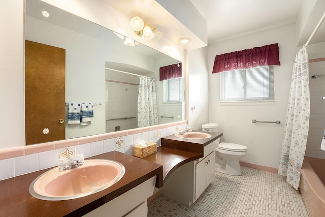 bathroom with double vanity, a sink, toilet, and tile patterned floors