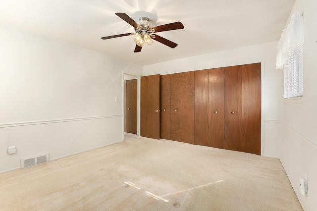 unfurnished bedroom featuring carpet, a closet, visible vents, and ceiling fan