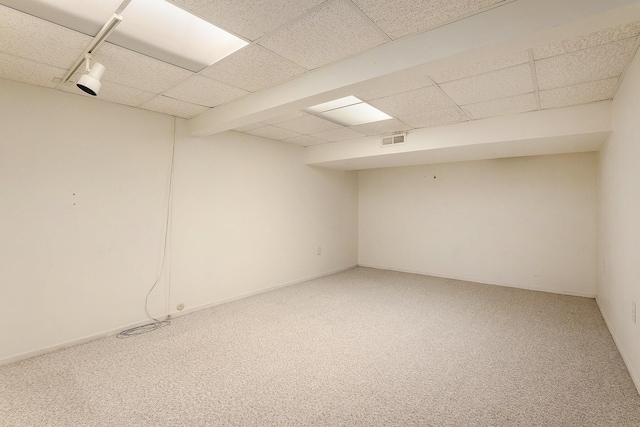 finished below grade area featuring a paneled ceiling, visible vents, and carpet flooring