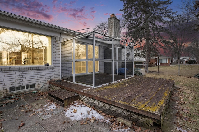 exterior space featuring a deck, brick siding, fence, a sunroom, and a chimney