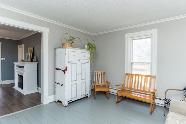 sitting room with a textured ceiling, ornamental molding, a fireplace, and wood finished floors