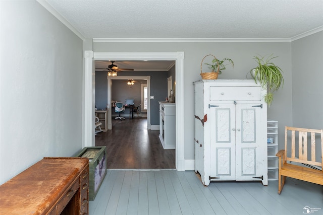 interior space with crown molding, a textured ceiling, baseboards, and wood finished floors