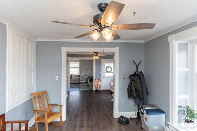 interior space with dark wood-style floors, baseboards, ornamental molding, and a textured ceiling