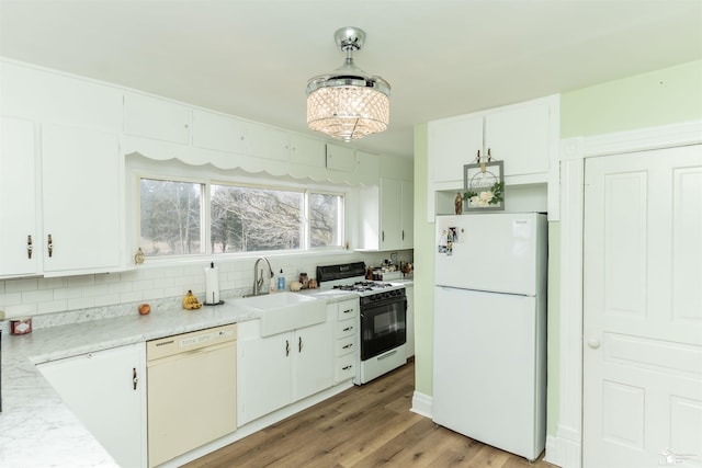 kitchen featuring light wood-style flooring, white appliances, a sink, white cabinets, and decorative backsplash