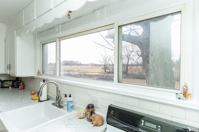 details featuring light countertops, backsplash, stove, white cabinetry, and a sink