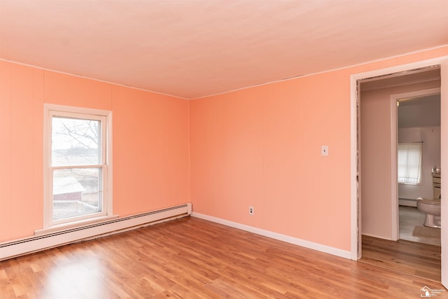 empty room with a baseboard heating unit, light wood-style floors, and baseboards