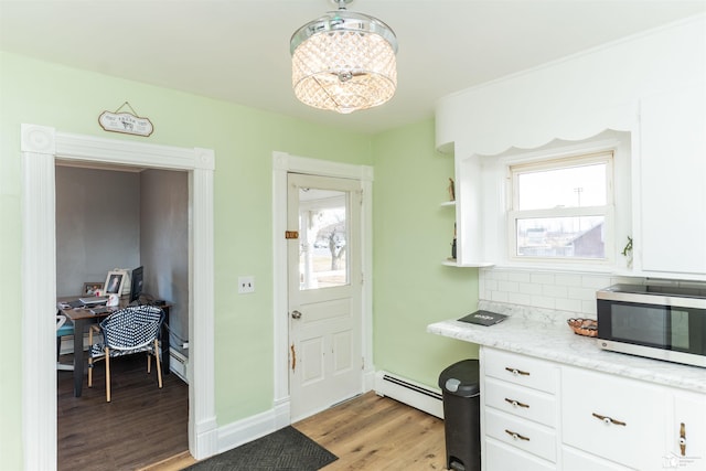 kitchen with stainless steel microwave, plenty of natural light, light wood finished floors, and baseboard heating