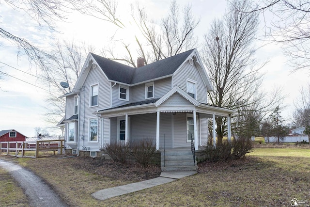 view of front of house featuring a porch, a chimney, a shingled roof, and fence