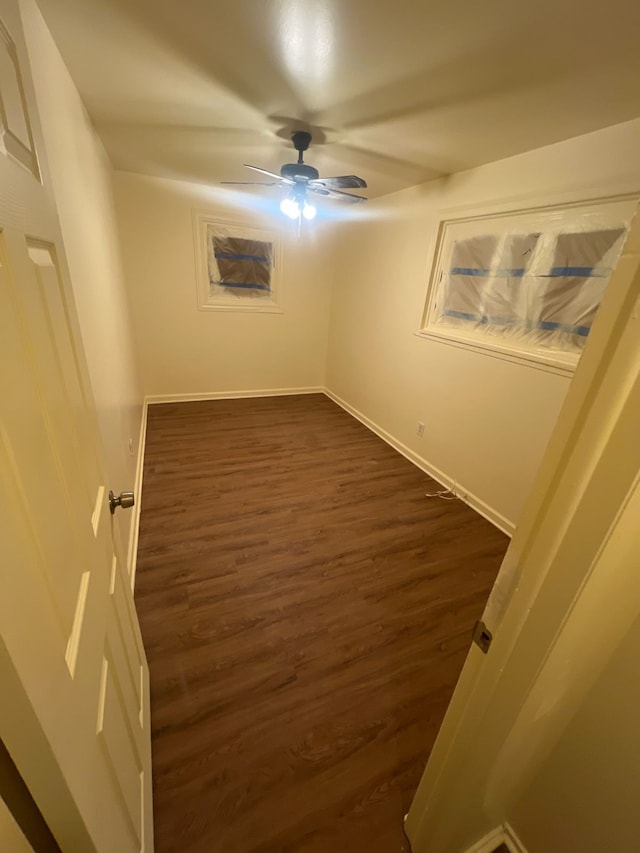 empty room with dark wood-style flooring, ceiling fan, and baseboards