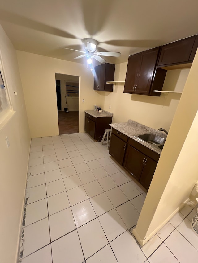 kitchen featuring light tile patterned floors, open shelves, a ceiling fan, a sink, and dark brown cabinets