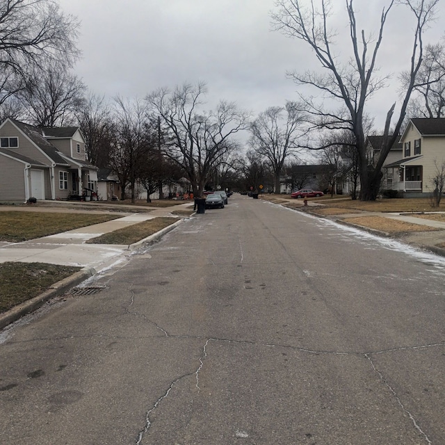 view of street featuring traffic signs, sidewalks, a residential view, and curbs