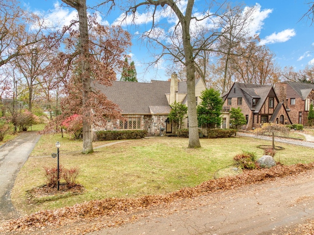 view of front facade featuring stone siding, a chimney, and a front lawn