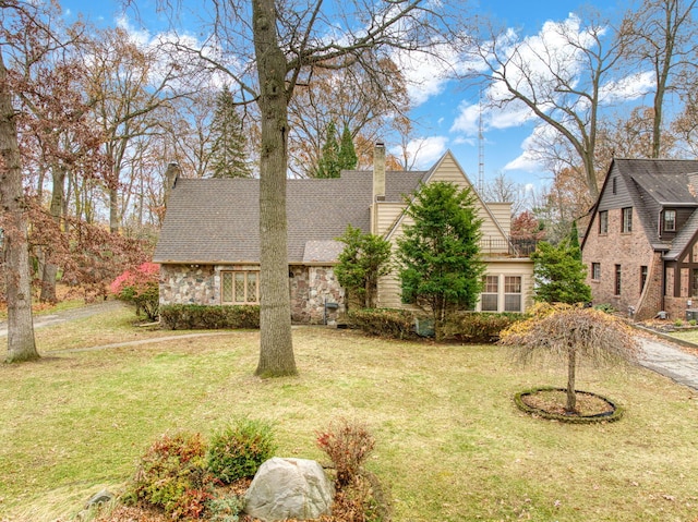 view of front of home with stone siding, a front lawn, and a chimney