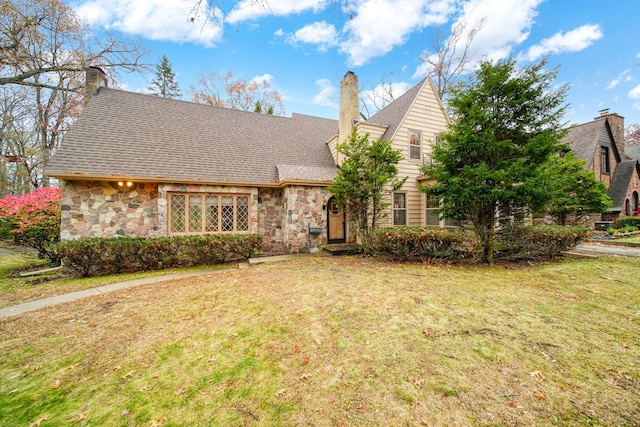 view of front of house with a front yard, stone siding, and a chimney