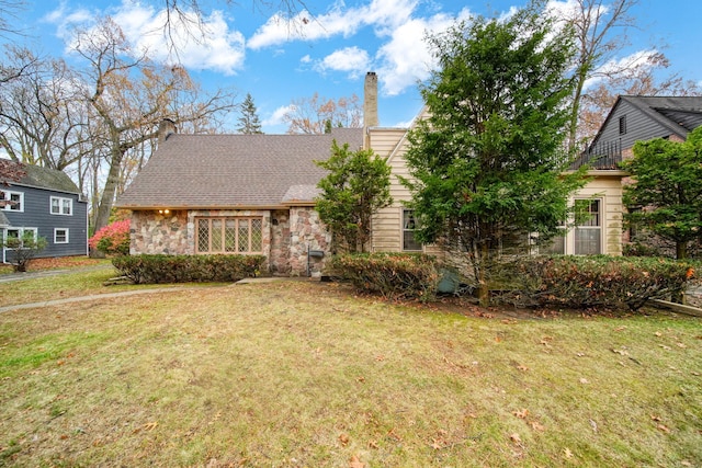 view of front of property with a front yard, stone siding, and a chimney