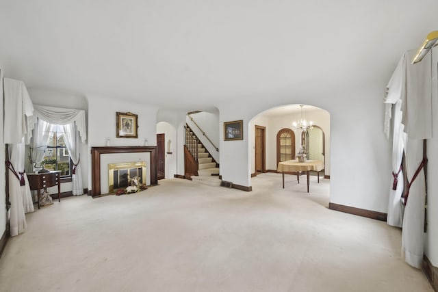 living room featuring arched walkways, carpet, stairway, a chandelier, and baseboards