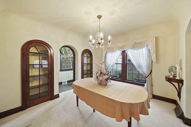 dining room with arched walkways, light colored carpet, baseboards, and an inviting chandelier