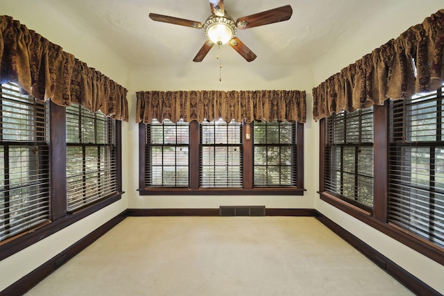 unfurnished sunroom with a ceiling fan and visible vents