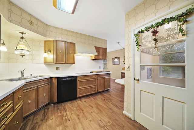 kitchen featuring exhaust hood, a sink, wood finished floors, dishwasher, and wallpapered walls