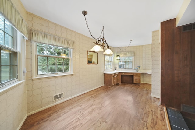 kitchen with wallpapered walls, visible vents, light countertops, and wood finished floors