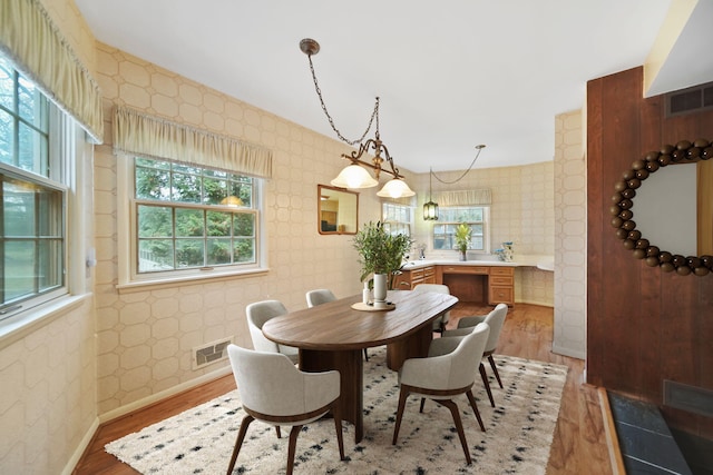 dining area with visible vents, light wood finished floors, baseboards, and wallpapered walls