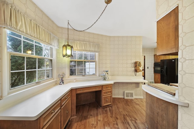 kitchen featuring black appliances, brown cabinets, visible vents, and wallpapered walls