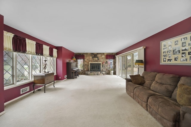 carpeted living room featuring visible vents, a stone fireplace, and baseboards