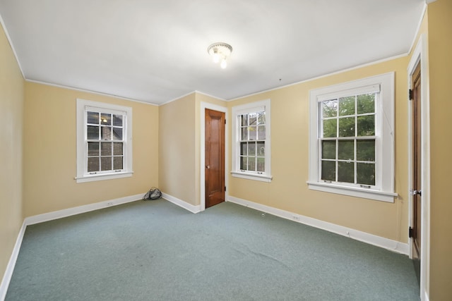 spare room featuring baseboards, dark colored carpet, and crown molding