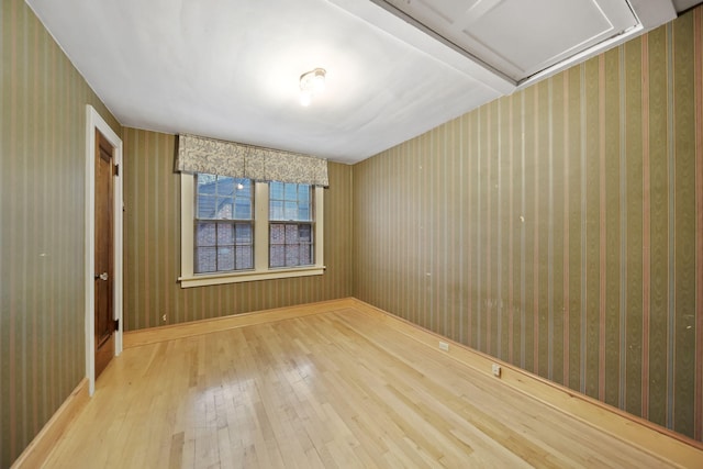 spare room with hardwood / wood-style floors and wallpapered walls