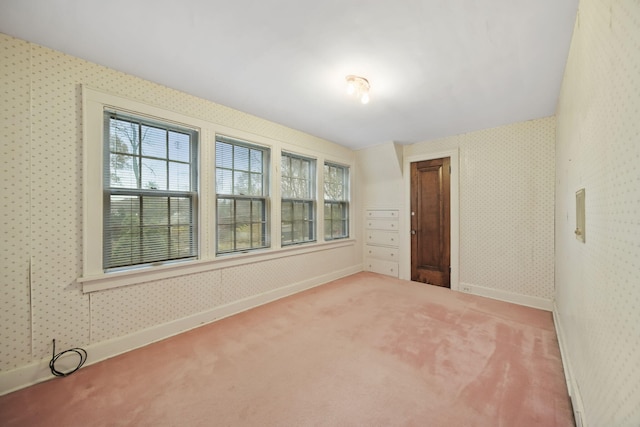 empty room with carpet floors, wallpapered walls, and baseboards