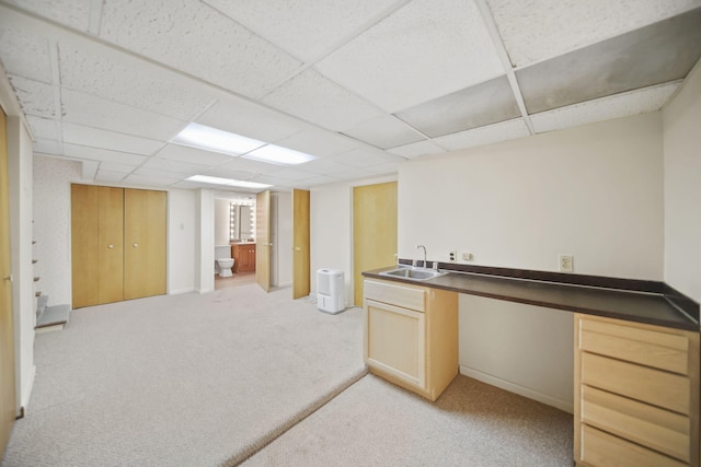 unfurnished office with a drop ceiling, a sink, and light colored carpet