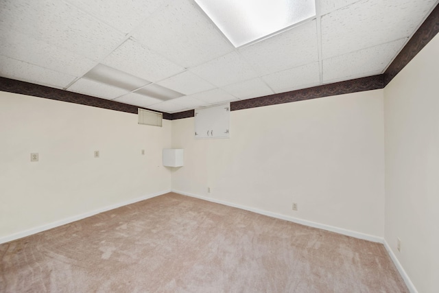 interior space with baseboards, a drop ceiling, and light colored carpet