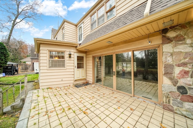 back of property featuring roof with shingles, fence, and a patio