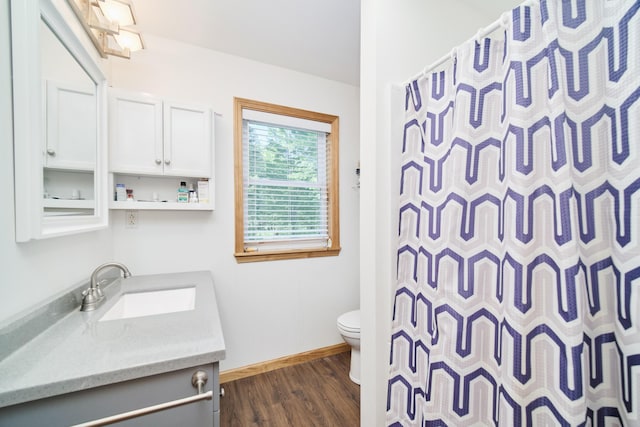 bathroom with curtained shower, toilet, vanity, wood finished floors, and baseboards