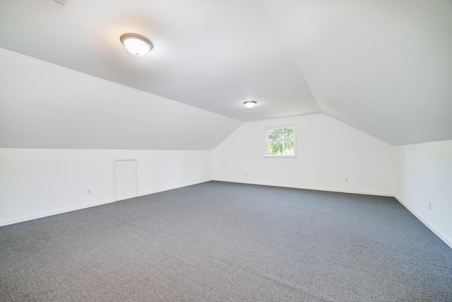 bonus room with lofted ceiling, dark carpet, and baseboards