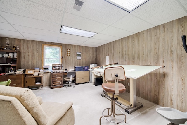 carpeted office featuring a paneled ceiling and wood walls