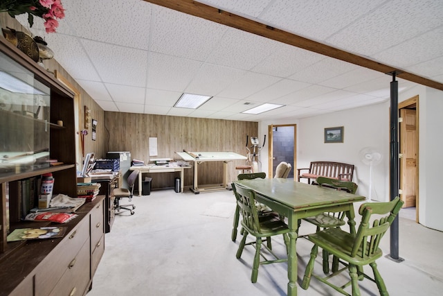 dining room featuring wooden walls and a drop ceiling