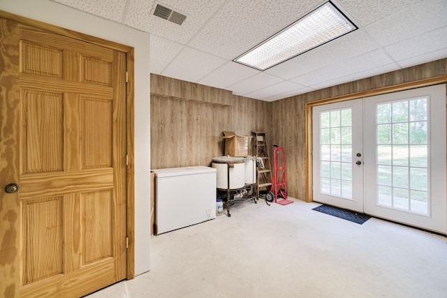 laundry room featuring french doors, visible vents, and wood walls