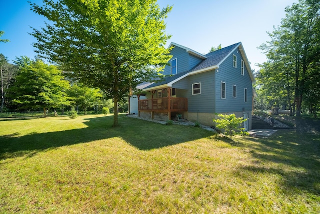 exterior space featuring a shingled roof, a lawn, and a wooden deck