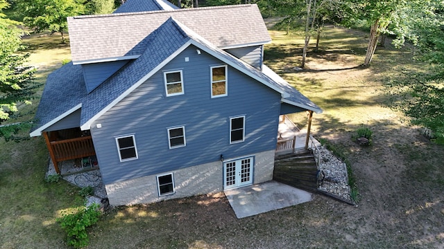 back of property with french doors, roof with shingles, and a patio area